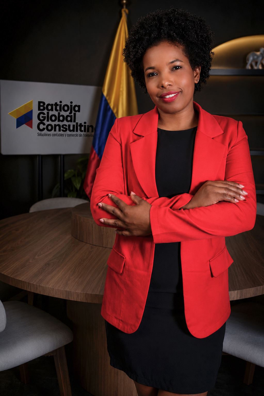 Luz Batioja con chaqueta roja junto a la bandera de Colombia y el logo de la empresa